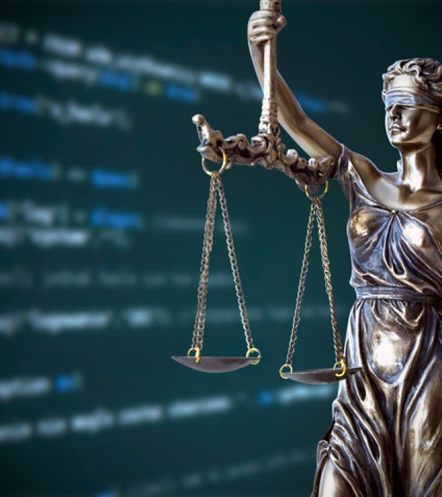 Justice statue with code on screen in background. Internet crime concept